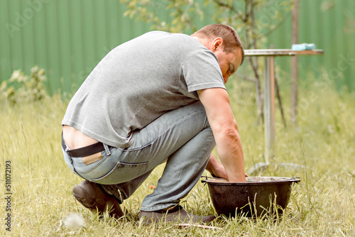 A man does his homework, cleans a cauldron in the backyard of a country house