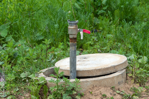 Technical concrete well with a pipe and a lever for water supply.