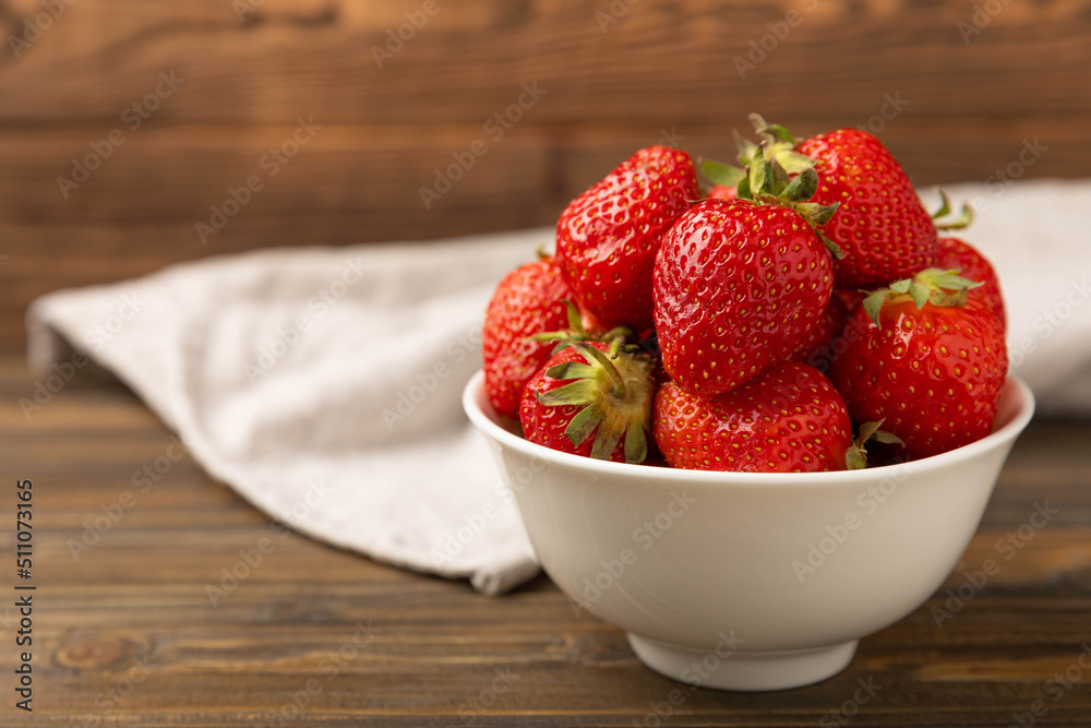 Fresh ripe strawberries in a bowl on a brown texture background.Vegetarian organic berry.Healthy food.Copy space.Place for text Fresh ripe strawberries in a bowl on a brown texture background.Vegetarian organic berry.Healthy food.Copy space.Place for text
