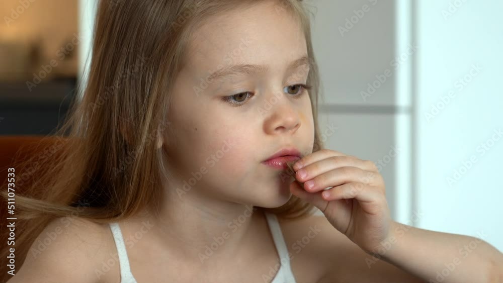 Close up of little child eats chocolate at home in kitchen. Happy child with chocolate candy. Dessert food sweetness Close up of little child eats chocolate at home in kitchen. Happy child with chocolate candy. Dessert food sweetness