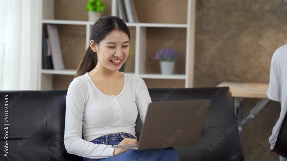 Asian woman using laptop at home, looking at screen, chatting, reading or writing email, sitting on couch, serious female student doing homework, working on research project online. Asian woman using laptop at home, looking at screen, chatting, reading or writing email, sitting on couch, serious female student doing homework, working on research project online.