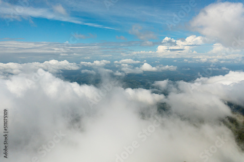 Top view through clouds of mountains with forest and valley with agricultural land. Sri Lanka.