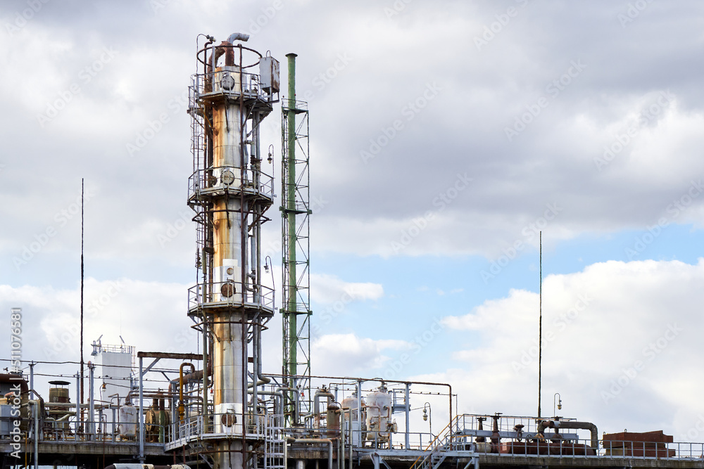 Old methanol distillation rectification refinery column towers under cloudy sky with lightning rod for lightning protection at petrochemical plant enterprise. Industrial background with copy space. Old methanol distillation rectification refinery column towers under cloudy sky with lightning rod for lightning protection at petrochemical plant enterprise. Industrial background with copy space.
