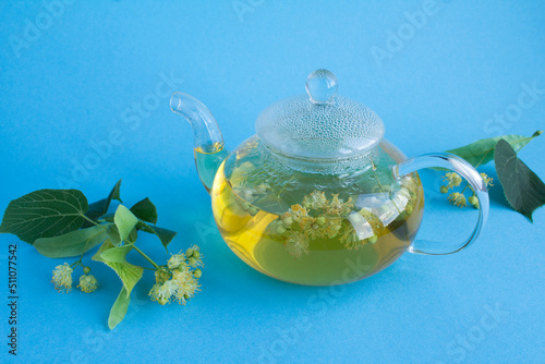 Tea with linden flower in the glass teapotn on the blue background. Closeup. photo