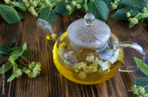 Tea with linden flower in the glass teapotn on the wooden background. Closeup. photo