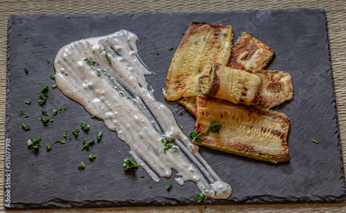 Grilled zucchini and tzatziki sauce - delicious greek style snack, tapas on a dark background, top view