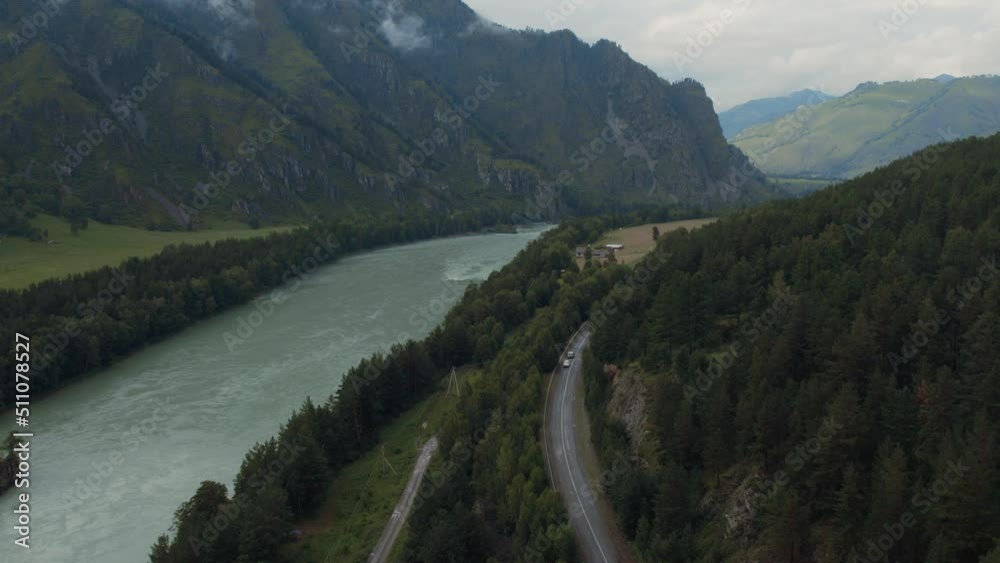 Katun river and traffic cars on road in mountains at during daytime, Altai, Siberia, Russia. Beautiful summer nature landscape at during daytime. Aerial view from a drone Katun river and traffic cars on road in mountains at during daytime, Altai, Siberia, Russia. Beautiful summer nature landscape at during daytime. Aerial view from a drone