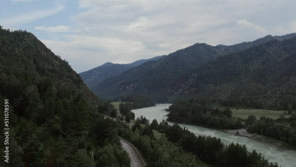 Mountains of Altai and traffic cars on road beside of Katun river at during daytime, Altai, Siberia, Russia. Beautiful summer nature landscape at during daytime. Aerial view from a drone Mountains of Altai and traffic cars on road beside of Katun river at during daytime, Altai, Siberia, Russia. Beautiful summer nature landscape at during daytime. Aerial view from a drone