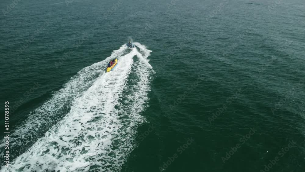 Aerial view of a jet ski pulling thrill seekers on an inflatable banana boat ride on a sunny South Florida day at the beach. Aerial view of a jet ski pulling thrill seekers on an inflatable banana boat ride on a sunny South Florida day at the beach.