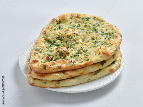 Garlic Naan Bread, A traditional Indian bread prepared with wheat flour, garlic, and coriander and baked in a vertical clay oven (tandoor), and then brushed with butter.