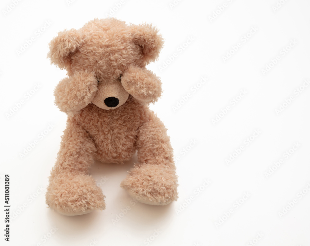 Obraz premium Child abuse concept. Teddy bear cover eye isolated on white background
