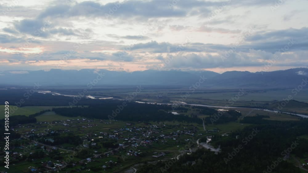 Aerial view of valley and country houses under blue sky in sunset time, Altai, Siberia, Russia. Beautiful summer nature landscape at during sunset. Aerial view from a drone Aerial view of valley and country houses under blue sky in sunset time, Altai, Siberia, Russia. Beautiful summer nature landscape at during sunset. Aerial view from a drone