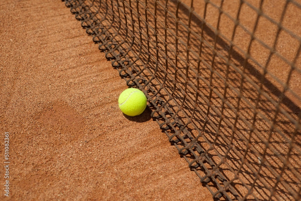 Tennis backgrounds. Ball on clay court and tennis net. Copy space for text.
