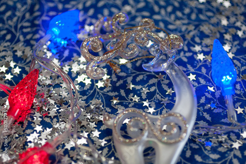 Closeup of the white deer with the golden horns, red and blue garland, silver stars on the blue and silver background. New year, Christmas background