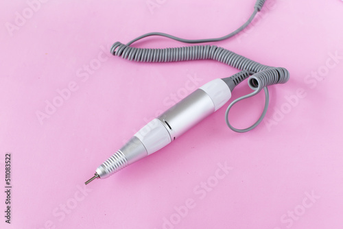 Special handle with a ceramic cutter for a professional female manicure and pedicure on a pink background. Specialized equipment for nail service