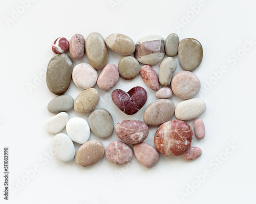 Aesthetic minimal pattern with set of sea pebbles and red heart stone on white background. Square composition from natural round smooth stone pink grey color. Summer, love, romance concept