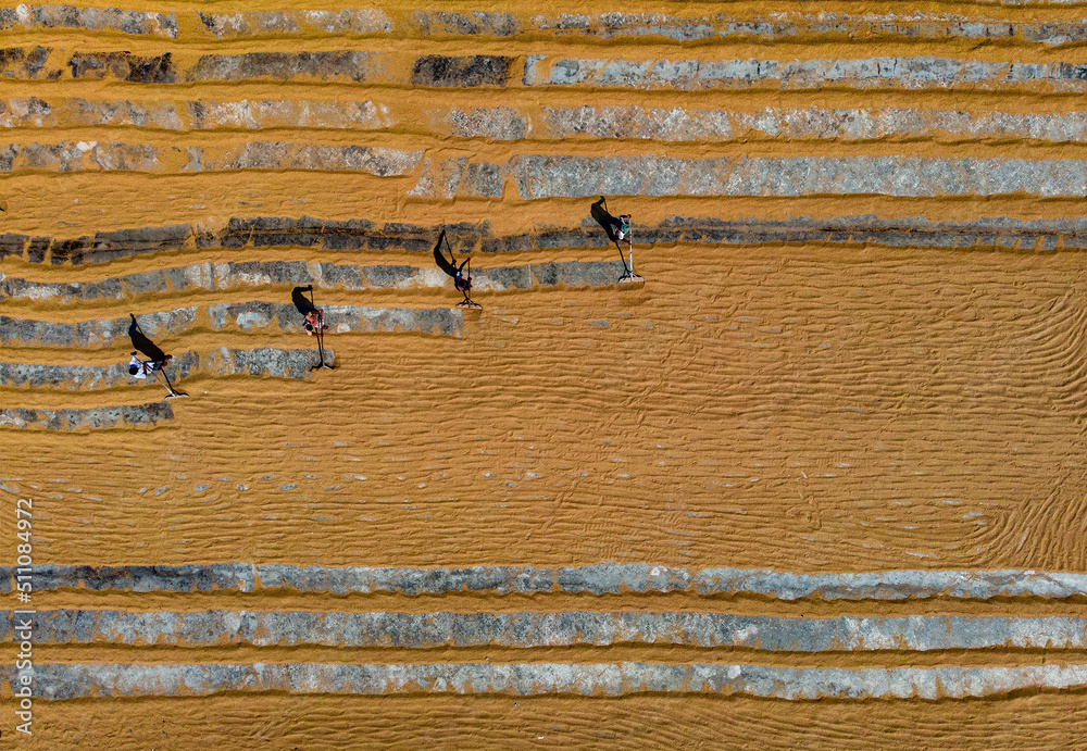 Workers working in small rice mill. Rice, paddy grain drying in sun. Flipping and weeping rice grains. Aerial view of rice mill. Workers working in small rice mill. Rice, paddy grain drying in sun. Flipping and weeping rice grains. Aerial view of rice mill.