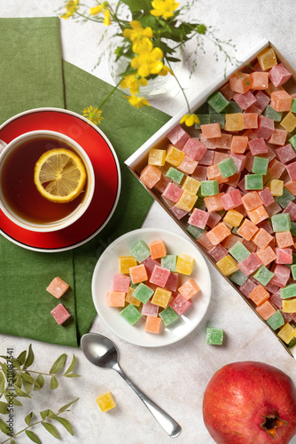 top view of a tea party - a cup of tea and a box with sweets in the form of multi-colored cubes of marmalade