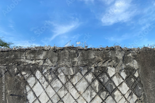 Broken flass bottle fence on concrete wall with isolated blue sky background. Thief and animal protection in concrete wall. Security. photo