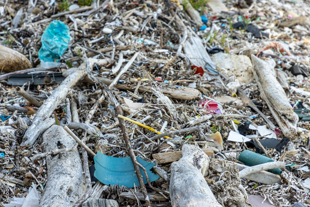 Plastic bottles and waste washed up on a beach by the incoming tide, covering the entire beach