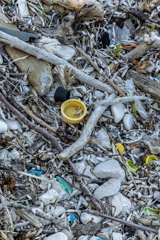 Plastic bottles and waste washed up on a beach by the incoming tide, covering the entire beach