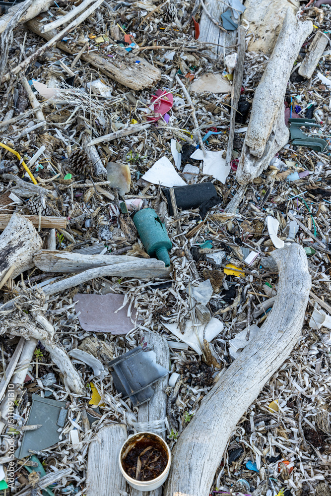 Plastic bottles and waste washed up on a beach by the incoming tide, covering the entire beach