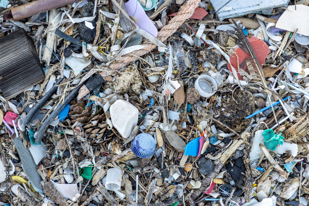 Plastic bottles and waste washed up on a beach by the incoming tide, covering the entire beach