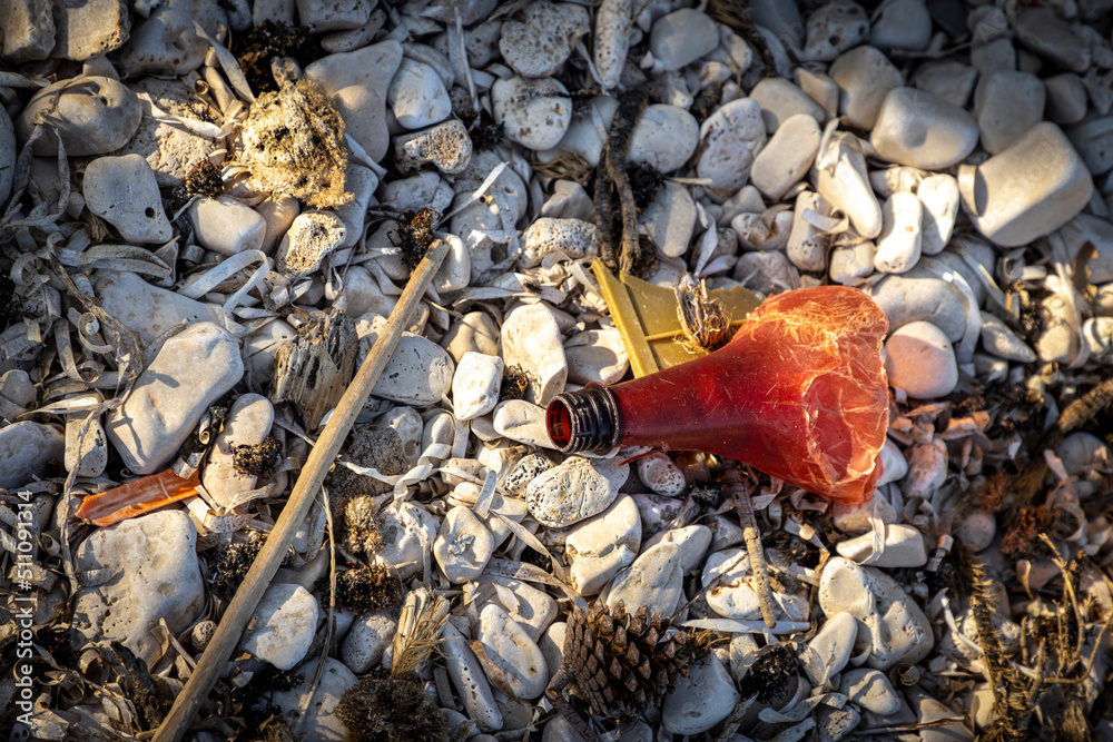 Plastic bottles and waste washed up on a beach by the incoming tide, covering the entire beach