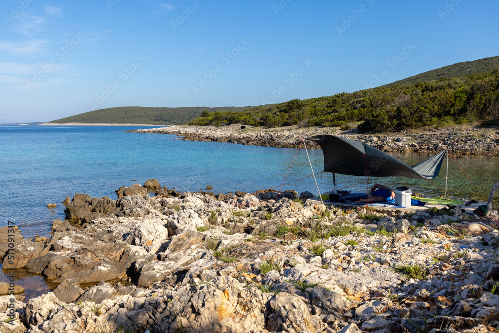 woman lying under awning on the coast of island Molat in Croatia