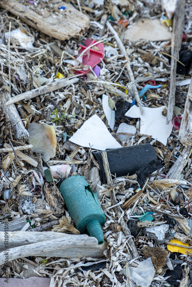 Plastic bottles and waste washed up on a beach by the incoming tide, covering the entire beach