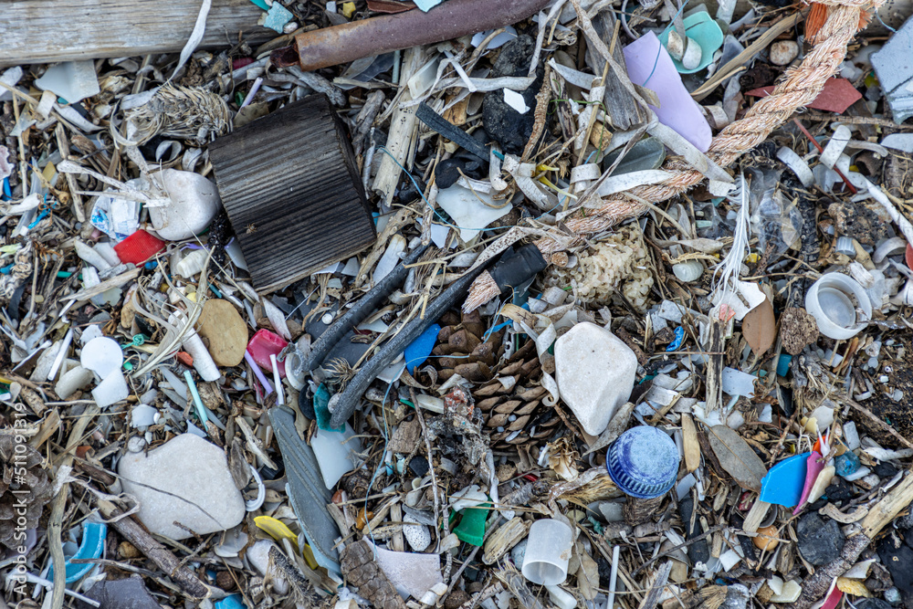 Plastic bottles and waste washed up on a beach by the incoming tide, covering the entire beach