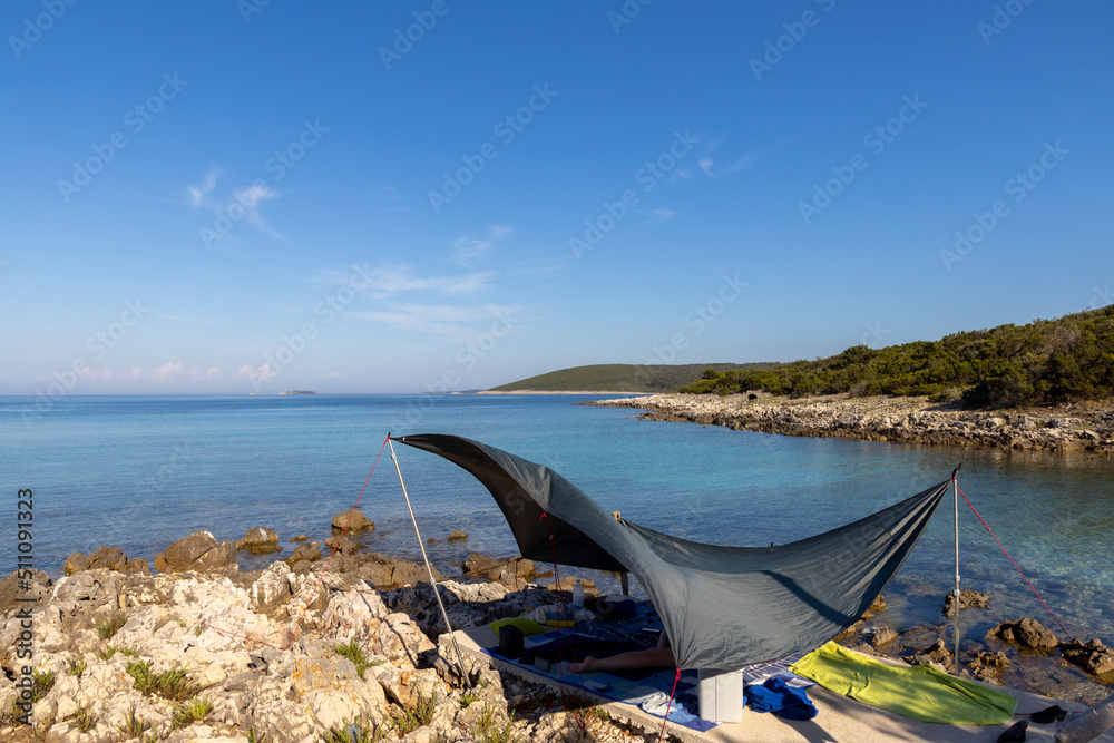 woman lying under awning on the coast of island Molat in Croatia