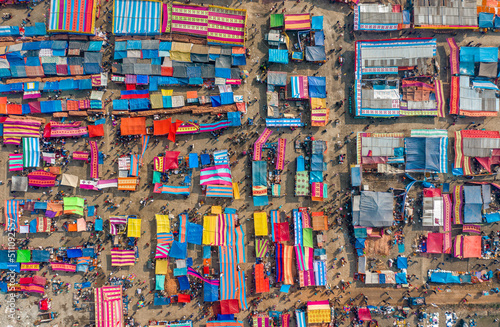 Aerial view of traditional village fair in Bangladesh. Colorful tents of temporary shops make it look like blocks of tetris game. Portable ferris wheel