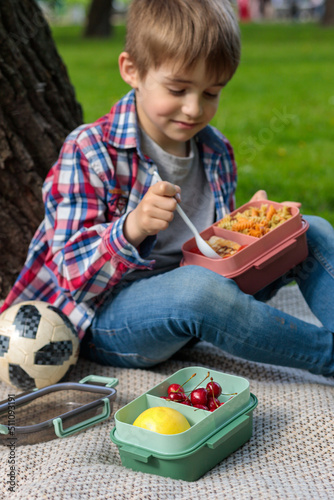 A boy on a picnic eats lunch. Vertical frame, selective focus