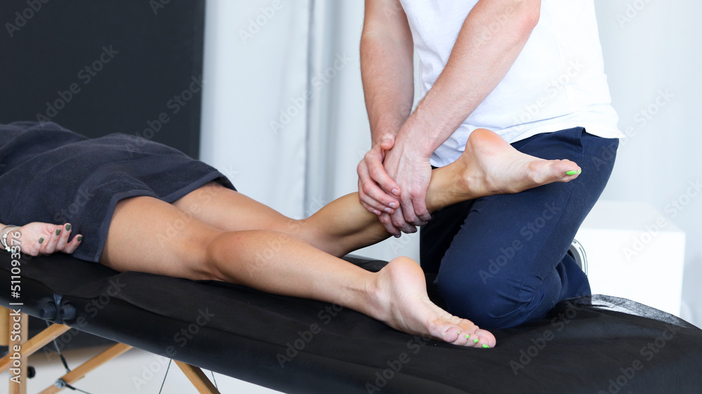 Masseur does legs massage in spa center. Massage of myofascial trigger points on leg of female client to release tension. Rehabilitation, sport therapy medicine. 