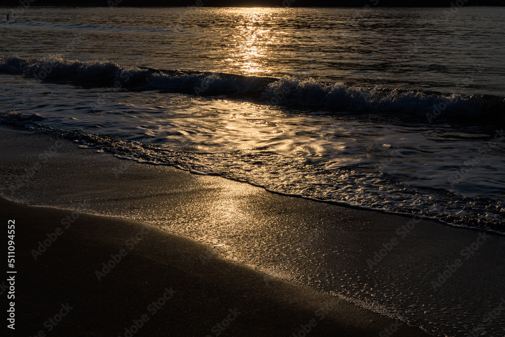 伊豆の弓ヶ浜の砂浜と波に反射する朝日の光