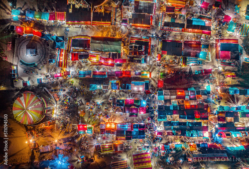Aerial view of traditional village fair in Bangladesh. Colorful tents of temporary shops make it look like blocks of tetris game.  Portable ferris wheel photo