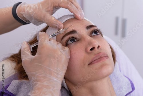 Cosmetologist performs rejuvenating anti-wrinkle filler injections with hyaluronic acid filler in a woman's face Female aesthetic cosmetology in a beauty salon.