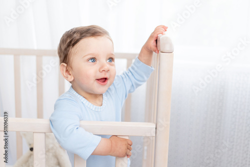 portrait of a baby boy in a crib in a children's room with big blue eyes