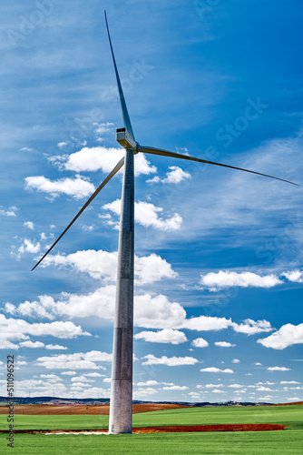 Field with windmills that generate electricity in the sunlight.