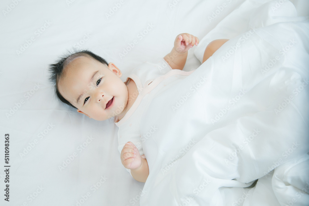 Cute little asian baby lying on bed with soft blanket indoors Cute little asian baby lying on bed with soft blanket indoors