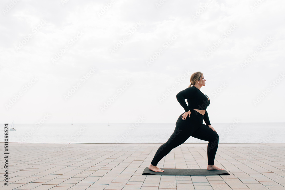 plus size girl practicing yoga in front of the ocean