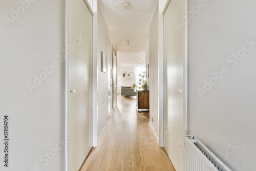 Принти на полотні Narrow corridor with white walls and doors leading to spacious room with windows