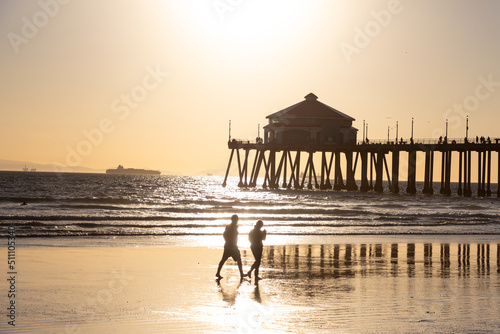 Couple Walking on Beach in Front of the Pier at Huntington Beach California at Sunset