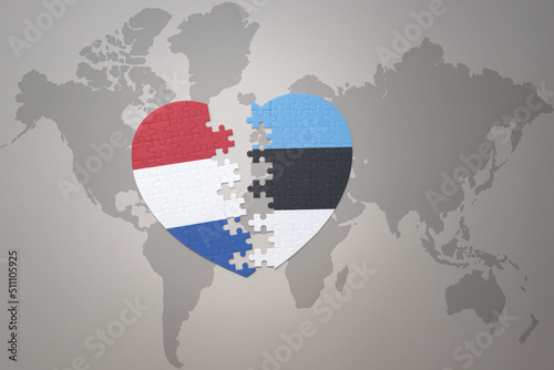 puzzle heart with the national flag of estonia and netherlands on a world map background.Concept.