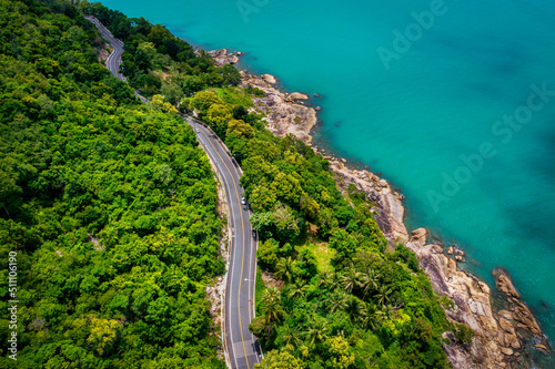 Aerial view of road between coconut palm tree and great ocean at daytime in Nakhon Si Thammarat, Thailand