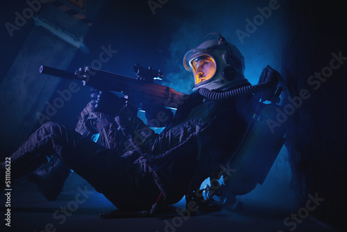Spaceman or star trooper in the helmet and with rifle in the blue smoke. Science fiction concept.