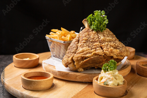 Pork knuckle Served with french fries and mashed potatoes on wooden cutting board