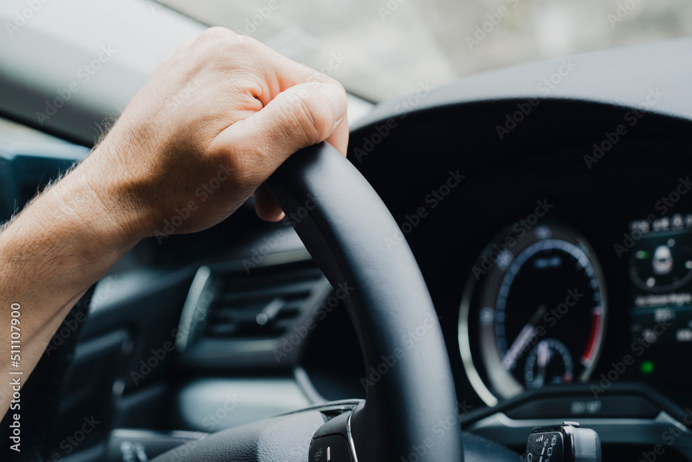 Male hands on a car's steering wheel
