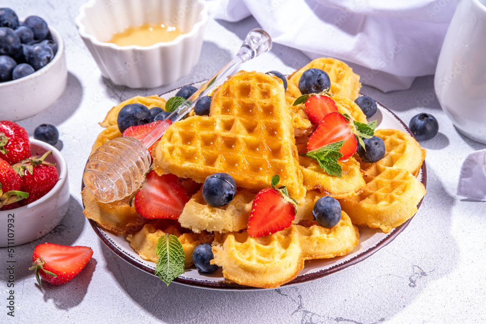 Breakfast belgian waffles with strawberries, blueberries and honey, homemade healthy heart shaped waffles on white kitchen tables copy space Breakfast belgian waffles with strawberries, blueberries and honey, homemade healthy heart shaped waffles on white kitchen tables copy space
